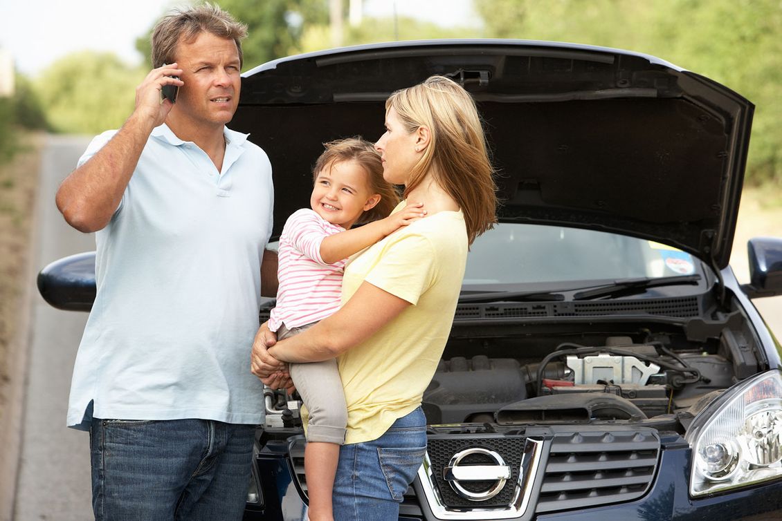 A family by the side of the road calling a mechanic after breaking down